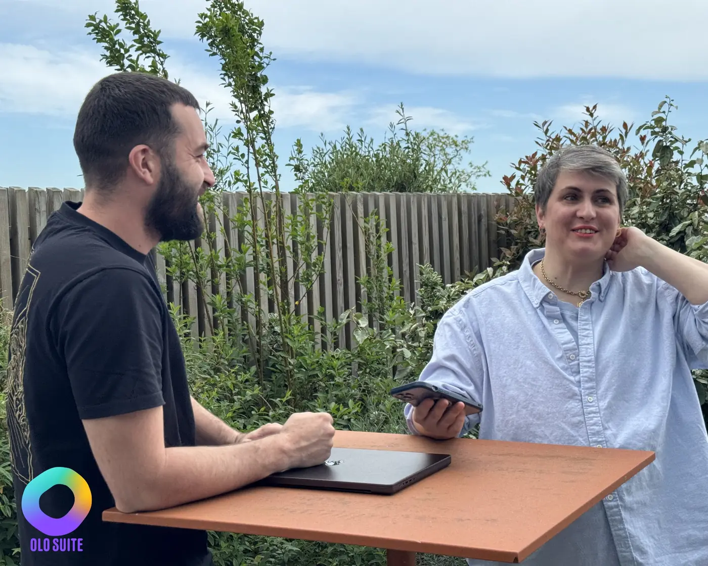Pierre, directeur de projet, et sa sponsor échangent debout autour d’une table, ordinateur et téléphone en main